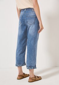 Lichtblauwe denim jeans met een losse pasvorm, verkorte lengte en contrasterende, gemusterde boorden. Voorzien van twee achterzakken en een label op de tailleband.