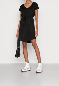 Schwarzes Kurzarmkleid mit V-Ausschnitt und verstellbarem Kordelzug in der Taille. Es hat eine lockere Passform und einen Saum, der oberhalb des Knies endet.