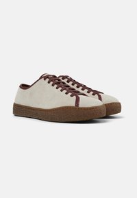 Beige suede sneakers with burgundy laces and accent stitching, featuring a textured brown rubber sole for grip and durability.