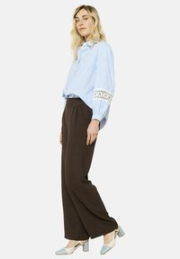 Blue and white striped blouse with lace detail at the cuffs, paired with brown wide-leg trousers and two-tone block-heel shoes.