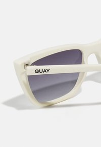 Hvite, kantete solbriller med gradient lilla linser. "QUAY"-logo på venstre arm. Elegant design og glatt tekstur.