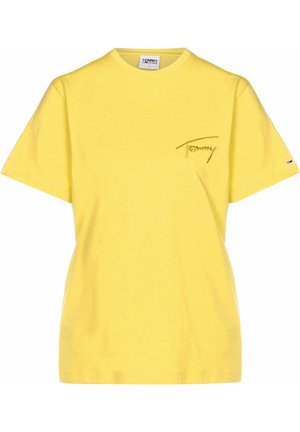 Żółta koszulka z krótkim rękawem i okrągłym dekoltem, z małym wyszywanym napisem „Tommy” na lewej piersi i małym logo flagi na lewym rękawie.
