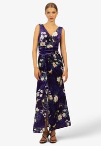 Fioletowa aksamitna suknia z kwiatowymi wzorami, dekolt w serek, drapowana konstrukcja, rozcięcie z boku oraz plisowane detale. Elegancka sylwetka do ziemi.