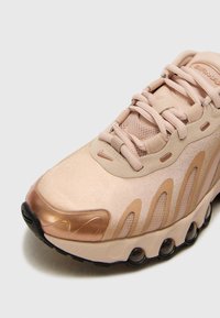 Lichtroze sneaker met een metallic roségouden neustip, meshpanelen en textuurdetails. Voorzien van ton-sur-ton veters en een zwarte rubberen loopzool.