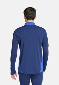 T-shirt de sport à manches longues en bleu profond avec des panneaux latéraux bleu clair ; tissu lisse, coutures plates et design de col.