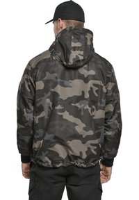 Chaqueta de camuflaje en tonos de gris y negro, con capucha, puños elásticos y dobladillo. Textura suave con cordón en la cintura.