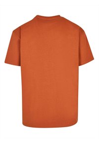 Tričko s krátkym rukávom v jednotnej spálenej oranžovej farbe, vyrobené z bavlny. Obsahuje okrúhly výstrih a rovný strih bez akýchkoľvek grafík alebo ozdôb.