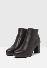 Brown leather ankle boots with a smooth texture, high block heel, elastic side panels, and a short zipper for easy wear.