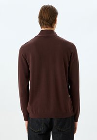 Brauner gestrickter Pullover mit Kragen, langen Ärmeln und geripptem Saum sowie Bündchen, von der Rückansicht gezeigt.