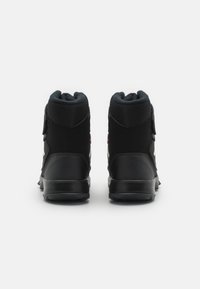 Czarne sneakersy typu high-top z teksturowaną cholewką, gumową podeszwą i kontrastującymi białymi akcentami po bokach. Regulowany pasek w okolicy kostki.