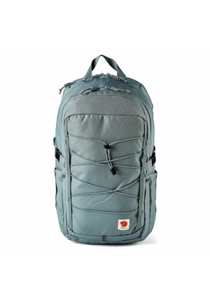 Zaino blu-grigio con cordino elastico frontale, molteplici scomparti con zip, tasche laterali e maniglia superiore per il trasporto, mostrato su sfondo bianco.