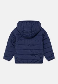 Giubbotto imbottito blu navy con cappuccio, caratterizzato da sezioni trapuntate e polsini elastici. Texture liscia, adatta per periodi di freddo.