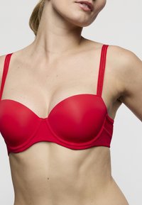 Rode gewatteerde beha met gladde cups en dunne verstelbare bandjes. Heeft een naadloos ontwerp met een matte afwerking en subtiele stikselaccenten.