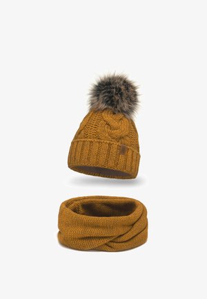 Gestrickte senfgelbe Mütze mit einem Kunstfell-Pompon und passendem Infinity-Schal, der ein strukturiertes Muster aufweist. Aus weichen und kuscheligen Materialien.