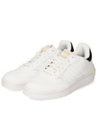 White sneakers with a smooth leather upper, three stripes design, and a padded black ankle collar; features gold branding accents.