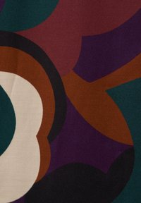 Tessuto multicolore caratterizzato da forme astratte in teal, bordeaux, nero e crema. Texture liscia con elementi grafici e contorni pronunciati.