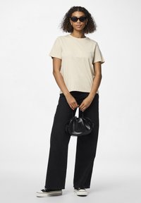 Beige bomulls t-skjorte, avslappet passform; svarte vide jeans; svart skinn minibag; svarte solbriller; svarte joggesko med hvite såler.