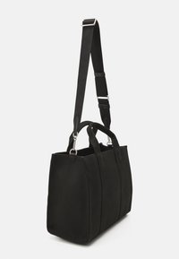 Svart kanvas tote väska med en strukturerad, rektangulär form; har dubbla korta handtag och ett avtagbart axelband med silverdetaljer.