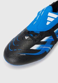 Nahaufnahme eines schwarz-blauen Fußballschuhs mit sleekem Design, strukturierten Oberflächen und Schnürsystem mit Branding-Elementen.
