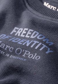 Sudadera gris oscuro con el texto gráfico "LIBERTAD DE IDENTIDAD" en azul y blanco, con cuello de canalé y una tela suave y texturizada.