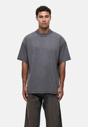 Grijze oversized t-shirt gemaakt van zachte katoen met een ronde halslijn en korte mouwen, gekenmerkt door een naadloos zijontwerp en een ontspannen pasvorm.