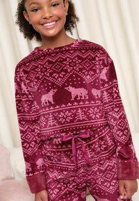 Conjunto de pijama de forro polar en burdeos con patrones de copos de nieve y animales en rosa, que cuenta con una cintura ajustable con cordón y una textura suave y esponjosa.