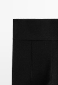 Zwarte high-waisted legging gemaakt van zachte stof, met een gladde textuur, platte naden en zonder zichtbare hardware of patronen.