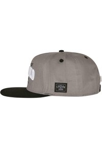 Cappellino snapback grigio con visiera nera, caratterizzato da testo bianco sulla parte anteriore e un patch del brand nero sul lato. Texture semplice.
