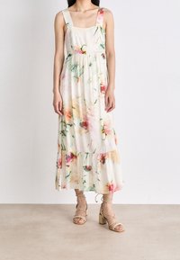 Robe maxi en tissu léger, ornée d'un imprimé floral dans des couleurs pastel, avec un décolleté carré, des bretelles larges et une taille froncée avec un ourlet volanté.