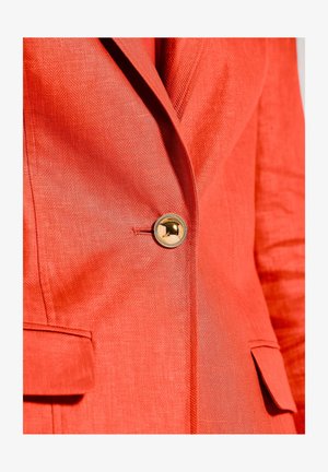 Red linen blazer featuring a herringbone texture, gold-tone button detailing, and two front pockets. Close-up view highlights material and design.