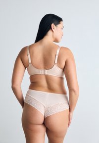Beige seamless bra and matching panties with lace trim. Adjustable straps and a hook closure on the bra. Soft, smooth texture.