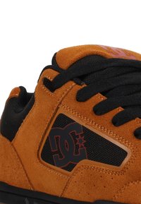Oranges Wildleder-Sneaker mit schwarzen Mesh-Akzenten, runden Schnürsenkeln und einem Logodetail. Verfügt über einen gepolsterten Kragen für Komfort und Langlebigkeit.