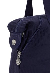 Granatowa torba nylonowa o strukturalnym designie, z metalowym suwakiem i detalem w postaci guzika. Teksturowana powierzchnia z ukośnymi liniami, miękkie wykończenie.