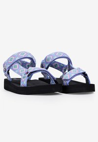 Sandalias azules con un diseño de patrón que presentan una correa trenzada con formas de diamante y una suela de espuma negra. Estilo ligero y casual.