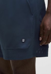 Granatowe spodenki sportowe z teksturowanym wykończeniem i siateczkowymi panelami. Posiadają naszywkę z logo oraz regularny krój z bocznymi kieszeniami.