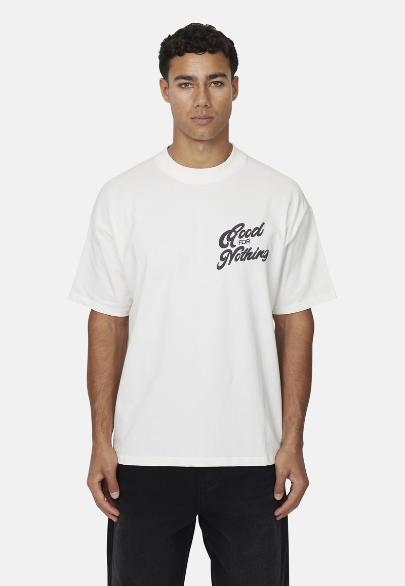 Biała koszulka wykonana z bawełny, z czarnym, kursywnym napisem "Good for Nothing" na lewej piersi. Luźny krój, okrągły dekolt.