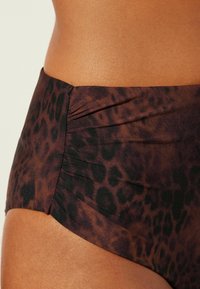 Bauchfreier Bikiniunterteil mit Leopardenmuster. Aus texturiertem Stoff mit gerafften Details in Braun- und Schwarztönen.