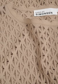 Bézs kötött felső, gyémántmintával, hullámos nyakkivágással és "KAREN BY SIMONSEN" feliratos címkével. Texturált anyag, nyitott szövettel.