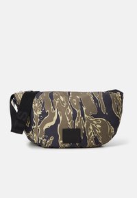 Marsupio con motivo camouflage nei colori oliva e blu navy, realizzato in tessuto resistente, con una cinghia nera e un patch con logo. Chiusura con zip.