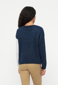 Marineblauer gestrickter Pullover mit lockerer Passform, langen Ärmeln und kontrastierenden hellgrauen Akzenten an den Ärmeln und am Kragen.
