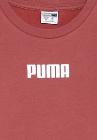 Camiseta de algodón color burdeos con cuello redondo y mangas cortas que presenta un destacado logo en blanco de "PUMA" en letras negritas en el pecho.