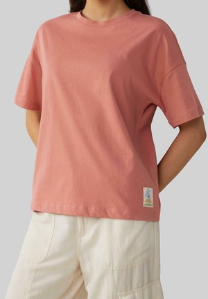 T-shirt à manches courtes en coton rose avec une coupe décontractée, présentant un petit écusson logo coloré sur l'ourlet et un col rond classique.