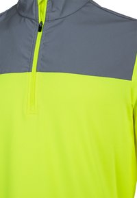 Høj synlighed pullover med en grå øverste del og en neongul nederste del, der har en kvart lynlås og en glat tekstur.