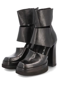 Black leather ankle boots with thick block heels, featuring a unique cut-out design and a smooth texture. Zipper on the side for closure.