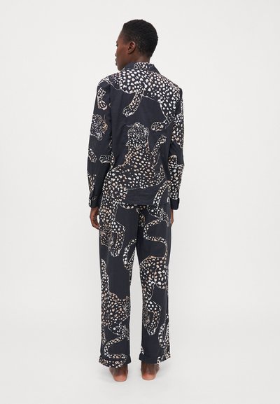 Súprava loungewear s vzorom so svetlými leopardími motívmi na tmavom pozadí. Vyrobené z ľahkej látky, obsahuje košeľu na gombíky a voľné nohavice.