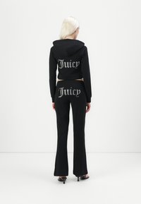 Czarna krótka bluza z kapturem z logo "Juicy" na plecach; dopasowane czarne dzwony z logo "Juicy". Gładki materiał, casualowy design.