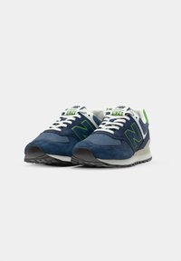 Blue suede sneakers with white accents and green logo. Features laces, logo on tongue, and textured sole for grip. Model number 574 displayed.