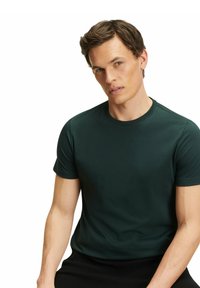 T-shirt verde scuro a maniche corte realizzato in tessuto liscio con scollatura rotonda. Design slim fit senza motivi o decorazioni visibili.