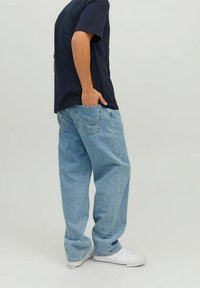 Ljust blå denimjeans med avslappnad passform, med en klassisk femfickdesign och sliten look, i kombination med vita sneakers.