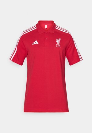 Červené polo tričko s bielym logom Adidas na pravej hrudi, emblém Liverpool FC na ľavej hrudi a tri biele pruhy na každom ramene.
